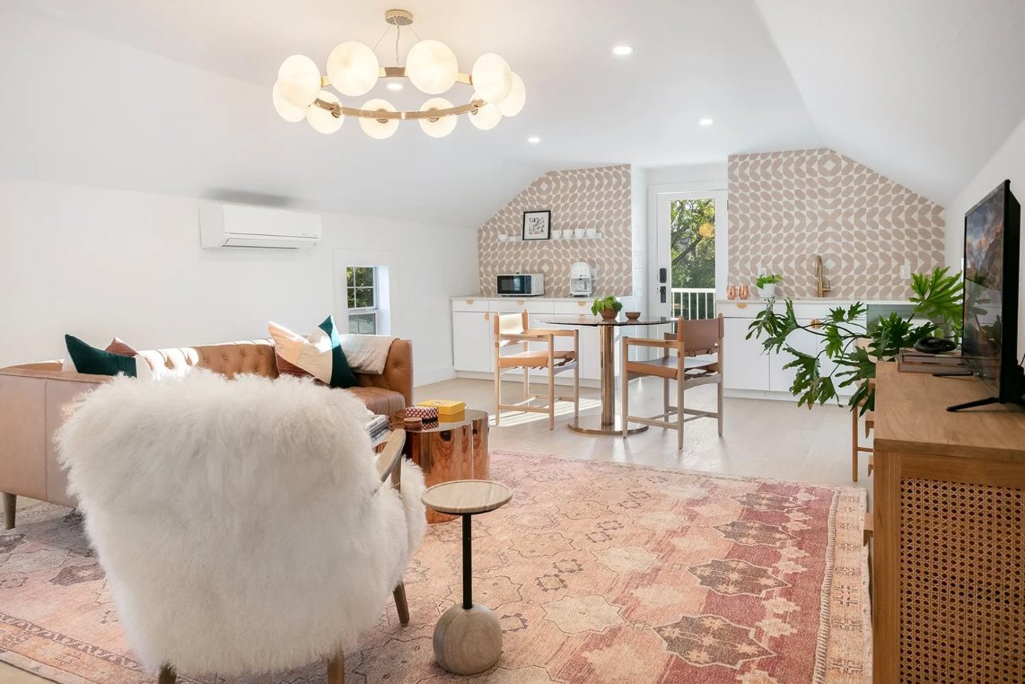 Light-filled upstairs living room with a globe chandelier, leather sofa and vintage rug