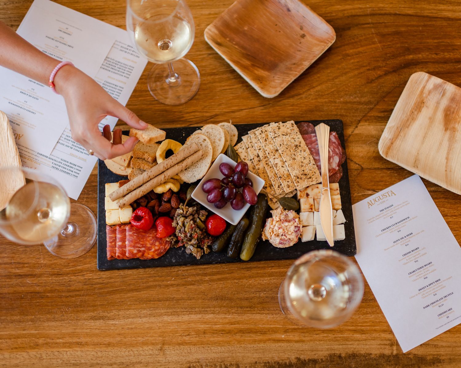 A charcuterie board with white wine and tasting notes on a wooden table