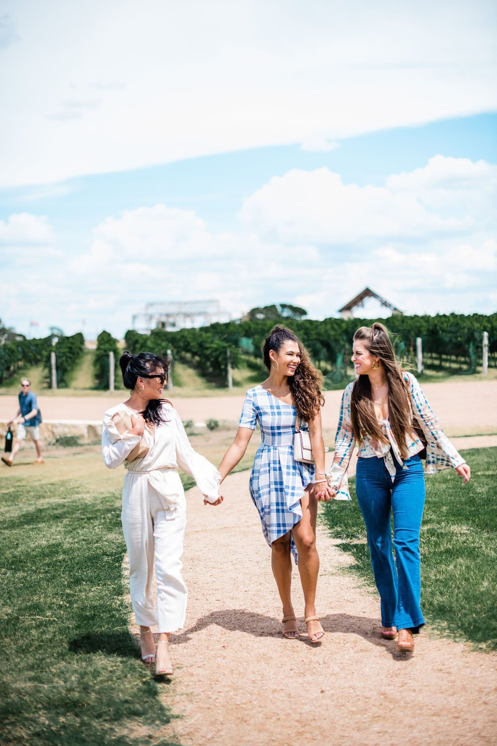 Three friends laughing as they walk a vineyard path in the Hill Country