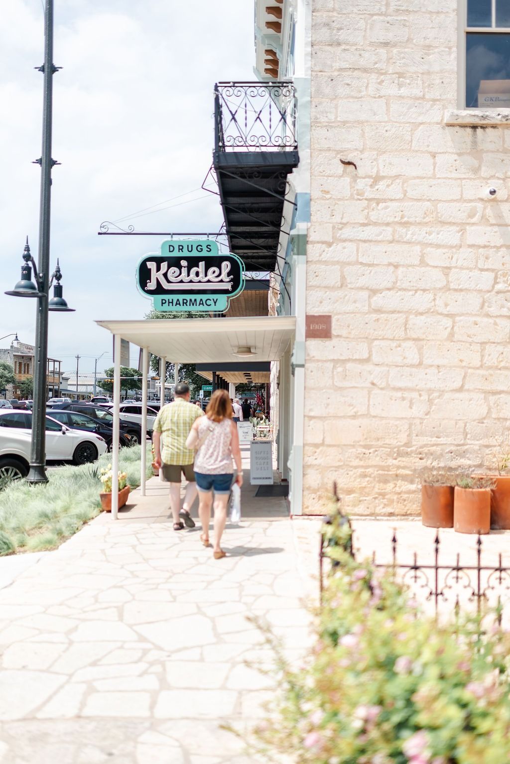 A couple strolling past historic limestone shops on Main Street in Fredericksburg