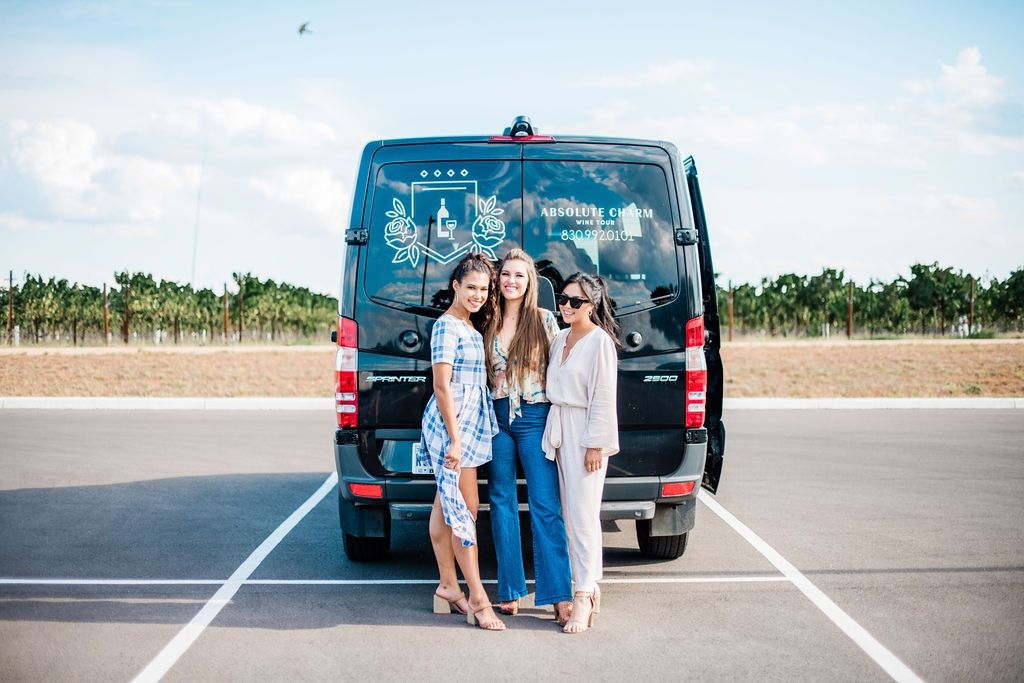 Three friends posing in front of the Absolute Charm Mercedes Sprinter at a vineyard