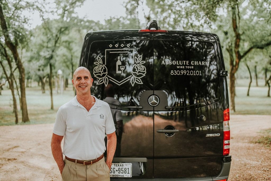 Barry smiling in front of the Absolute Charm Wine Tours Sprinter van under the live oaks