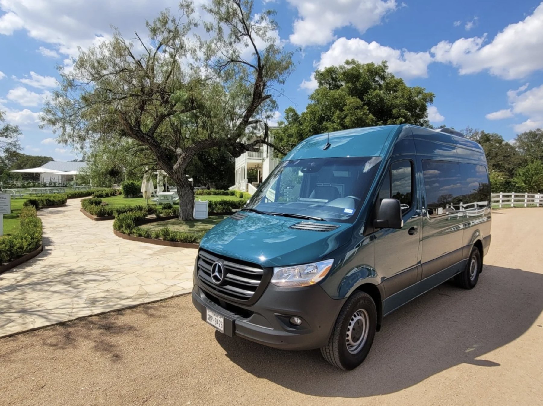 The teal Absolute Charm Mercedes-Benz Sprinter van parked at a Hill Country winery